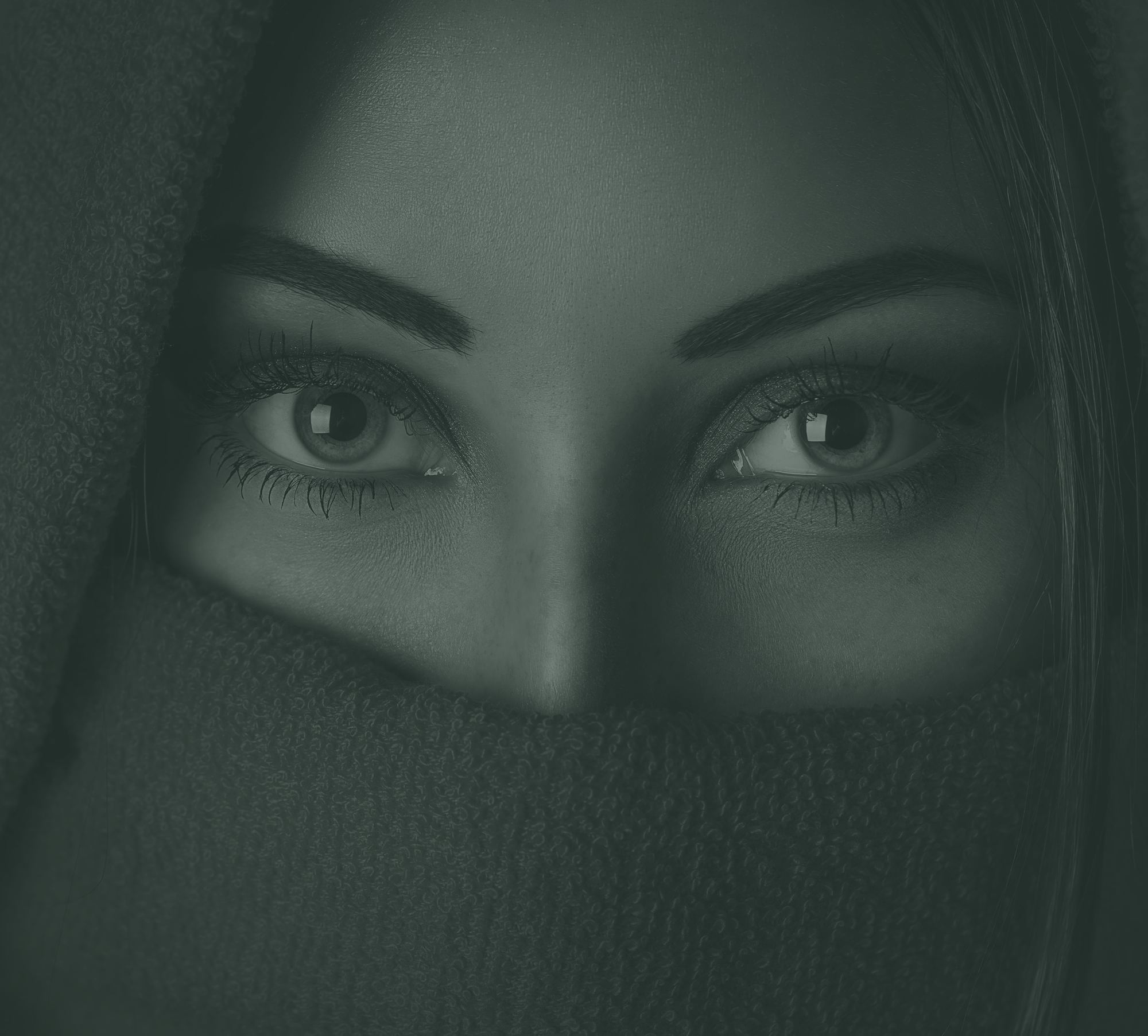 Close-up of a woman's eyes, shown in soft green tones